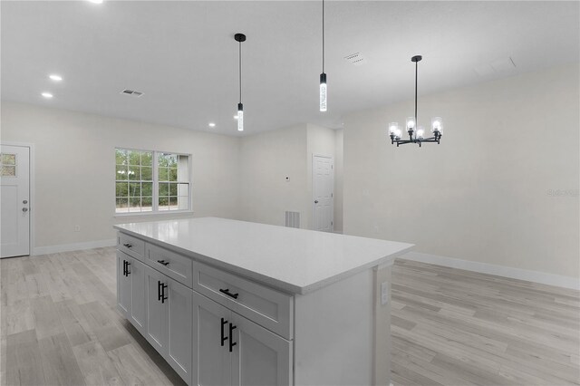 kitchen with hanging light fixtures, white cabinetry, a center island, and light hardwood / wood-style floors