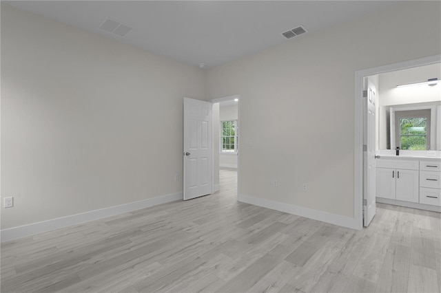 spare room with sink, plenty of natural light, and light wood-type flooring