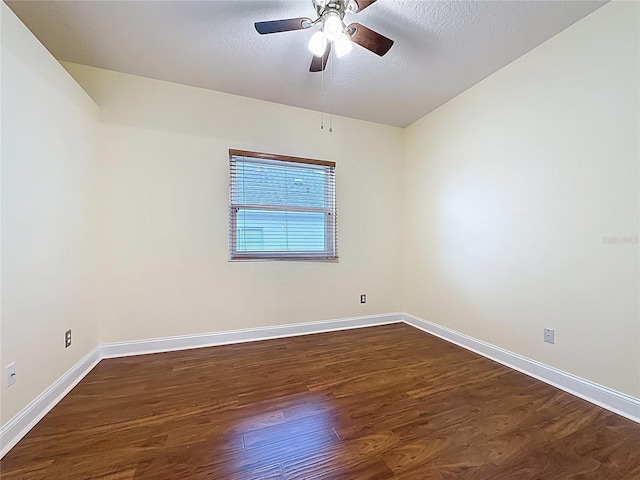 spare room featuring a textured ceiling, ceiling fan, dark wood finished floors, and baseboards