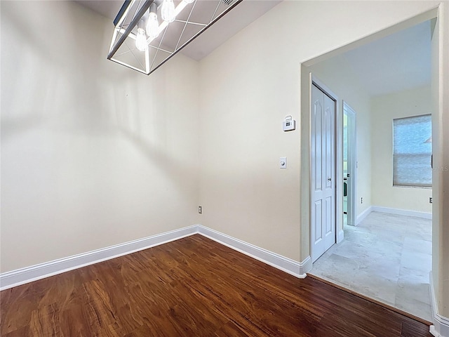 spare room featuring baseboards and wood finished floors