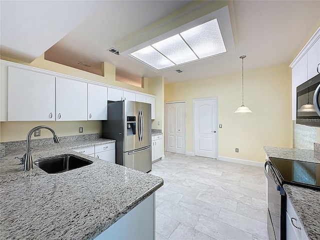 kitchen with decorative light fixtures, stainless steel appliances, white cabinetry, a sink, and light stone countertops