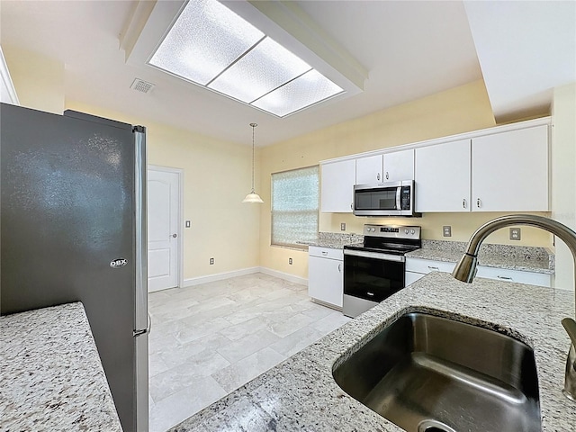 kitchen featuring visible vents, light stone counters, stainless steel appliances, white cabinetry, and a sink