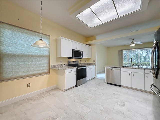 kitchen with hanging light fixtures, white cabinetry, stainless steel appliances, and a sink