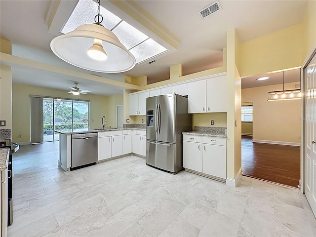 kitchen featuring a peninsula, a sink, visible vents, white cabinets, and appliances with stainless steel finishes