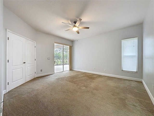 carpeted empty room featuring baseboards and a ceiling fan