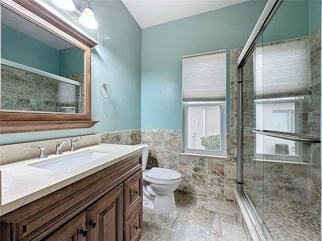 bathroom featuring a stall shower, vanity, tile walls, and stone tile floors