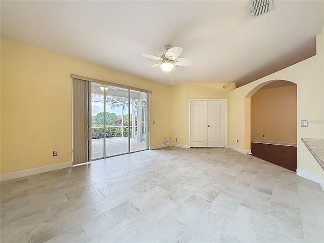 spare room with baseboards, visible vents, arched walkways, and a ceiling fan