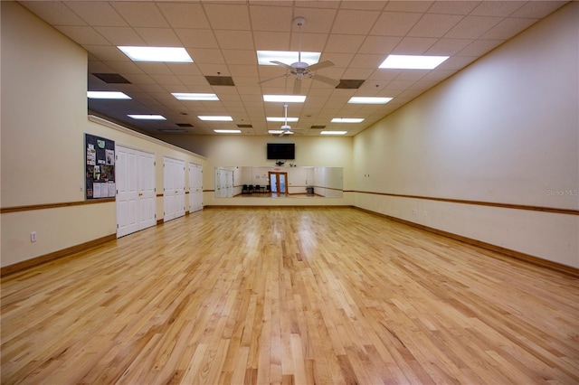 spare room with baseboards, a ceiling fan, a drop ceiling, and wood finished floors