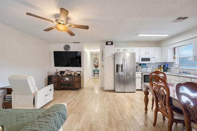 kitchen featuring sink, white cabinetry, backsplash, stainless steel appliances, and light wood-type flooring