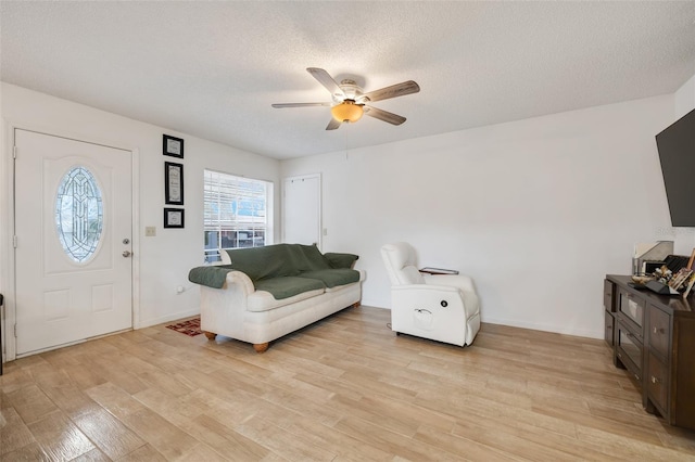 living room featuring ceiling fan, a textured ceiling, and light wood-type flooring