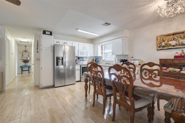 dining space featuring sink, a textured ceiling, and light wood-type flooring