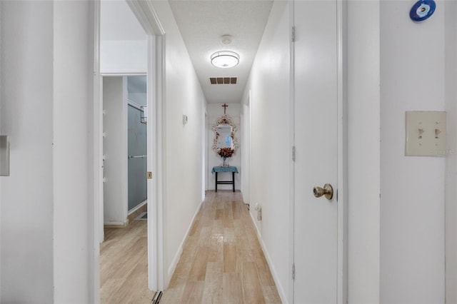 hallway featuring light hardwood / wood-style floors and a textured ceiling