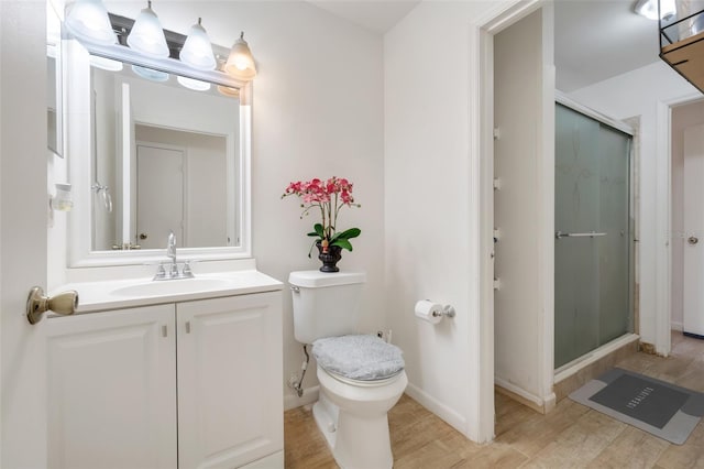 bathroom featuring a shower with door, vanity, hardwood / wood-style flooring, and toilet