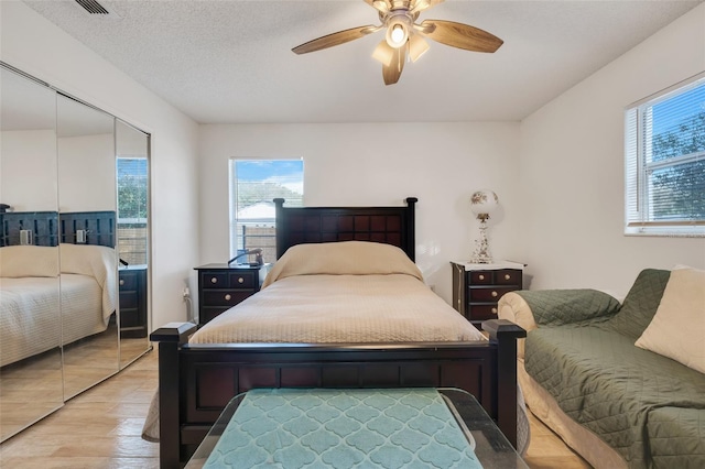 bedroom featuring a textured ceiling, ceiling fan, and light wood-type flooring