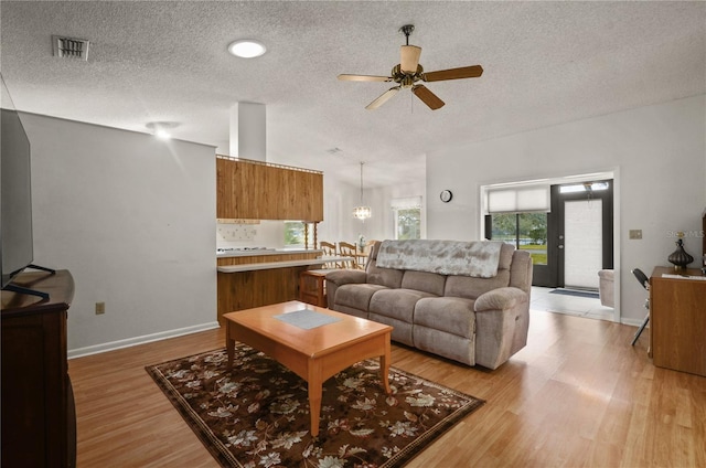 living room featuring a textured ceiling, ceiling fan, and light wood-type flooring