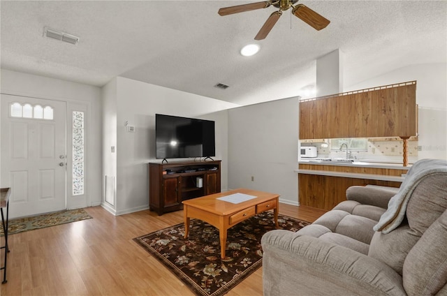 living room with lofted ceiling, light hardwood / wood-style flooring, and a textured ceiling