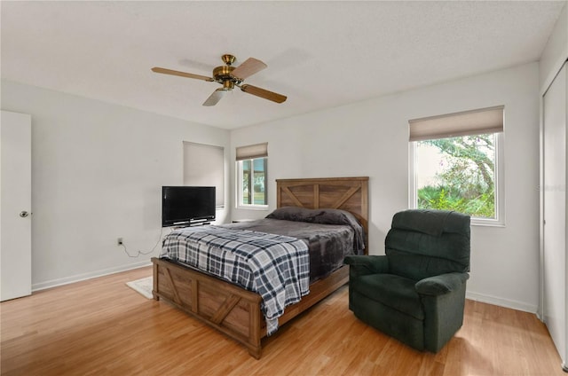 bedroom with multiple windows, ceiling fan, and light hardwood / wood-style flooring