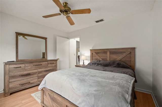 bedroom with a textured ceiling, light hardwood / wood-style flooring, and ceiling fan