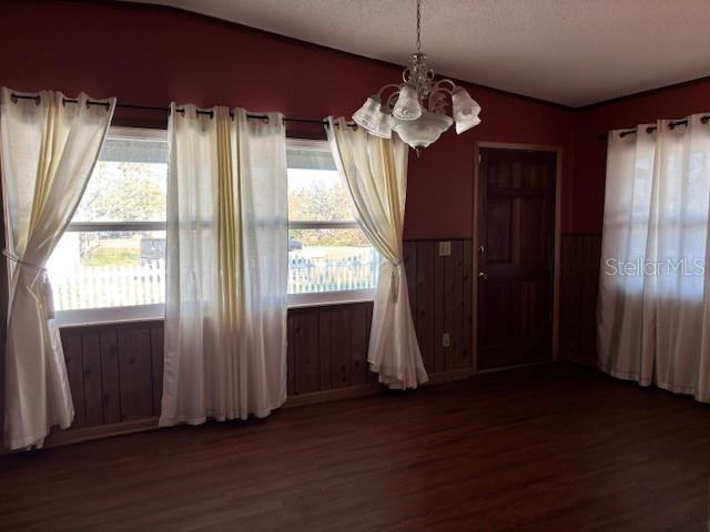 unfurnished dining area with dark hardwood / wood-style floors, a textured ceiling, and a chandelier