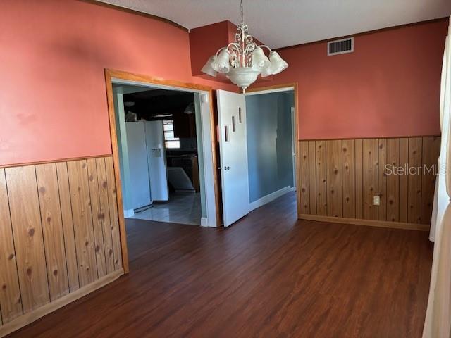 unfurnished dining area featuring a notable chandelier and dark hardwood / wood-style flooring