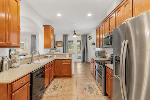 kitchen featuring appliances with stainless steel finishes, sink, light tile patterned floors, ceiling fan, and kitchen peninsula