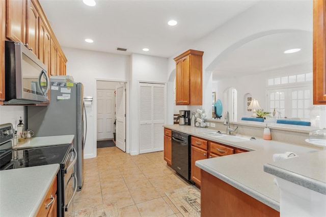 kitchen featuring appliances with stainless steel finishes, sink, light tile patterned floors, and kitchen peninsula