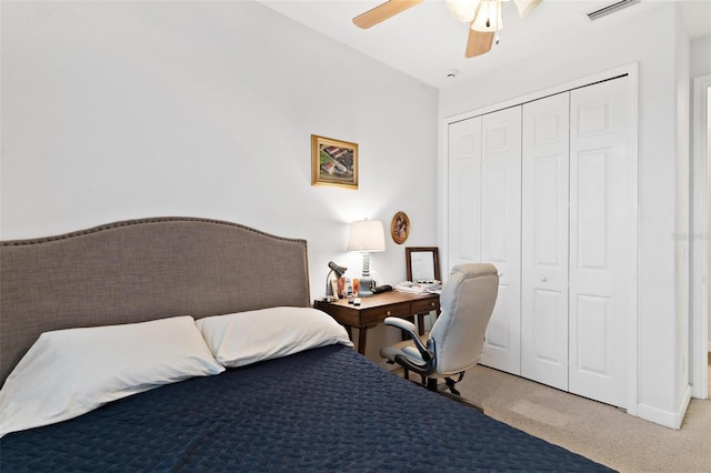 bedroom with ceiling fan, light carpet, and a closet