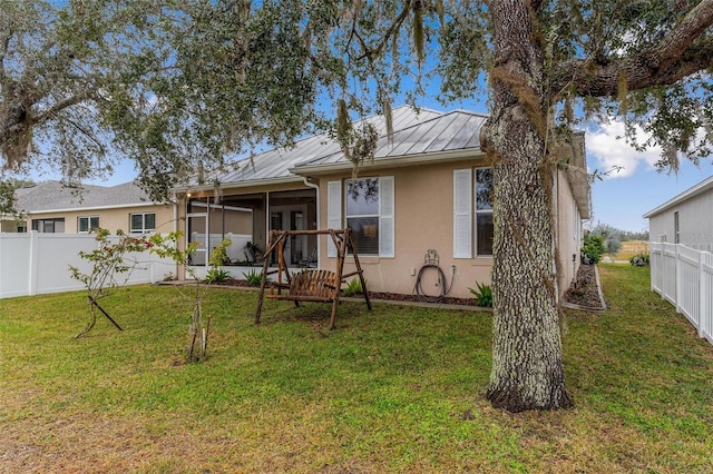 rear view of property with a sunroom and a lawn