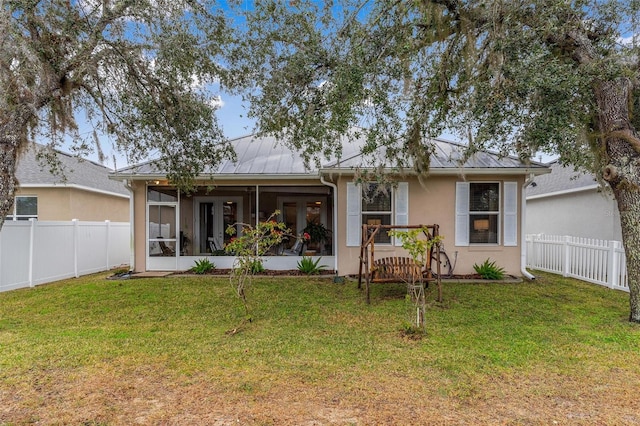 back of property with a sunroom and a lawn