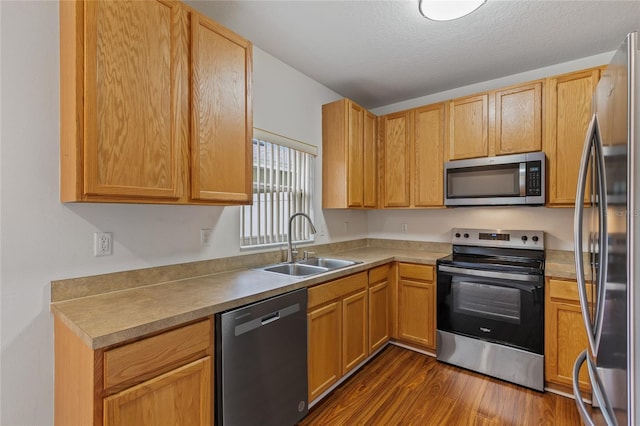 kitchen with appliances with stainless steel finishes, dark hardwood / wood-style flooring, sink, and a textured ceiling