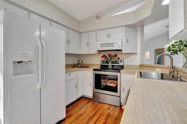 kitchen with sink, white appliances, vaulted ceiling, and white cabinets