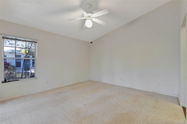 spare room featuring light carpet, vaulted ceiling, and ceiling fan