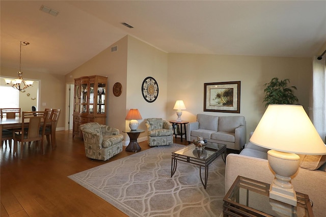 living room with vaulted ceiling, hardwood / wood-style floors, and an inviting chandelier