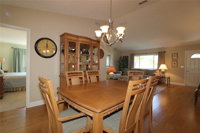 dining room featuring lofted ceiling, a notable chandelier, and dark hardwood / wood-style flooring