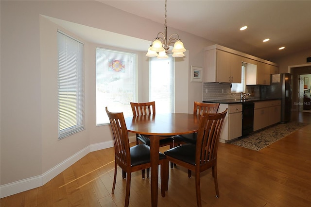 dining space featuring lofted ceiling, sink, a chandelier, and light hardwood / wood-style floors