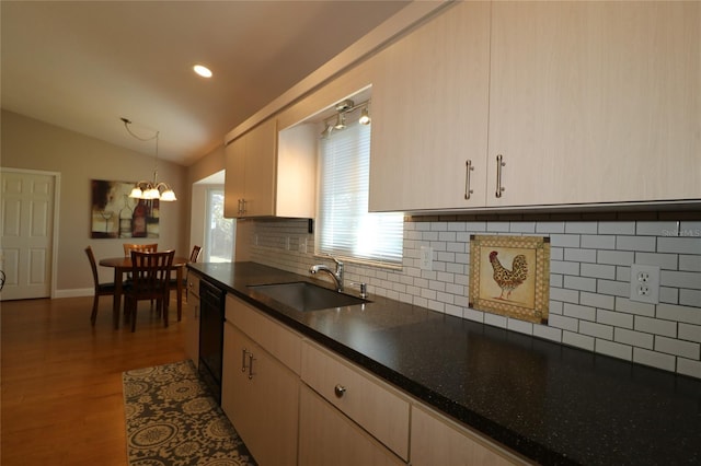 kitchen with lofted ceiling, light brown cabinetry, sink, decorative light fixtures, and black dishwasher