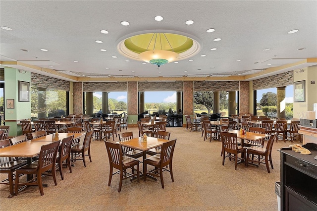 carpeted dining area featuring a textured ceiling and a tray ceiling