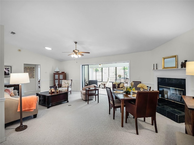 carpeted dining space with vaulted ceiling, ceiling fan, and a fireplace