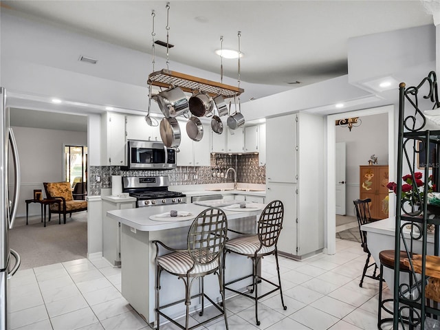 kitchen with sink, white cabinetry, a center island, stainless steel appliances, and decorative backsplash