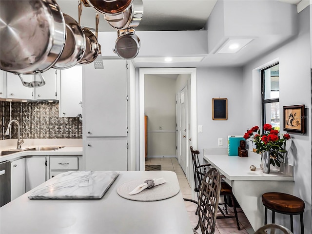 kitchen with white cabinetry, sink, light tile patterned floors, and backsplash