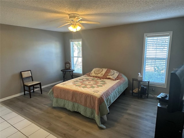 bedroom featuring multiple windows, hardwood / wood-style flooring, a textured ceiling, and ceiling fan