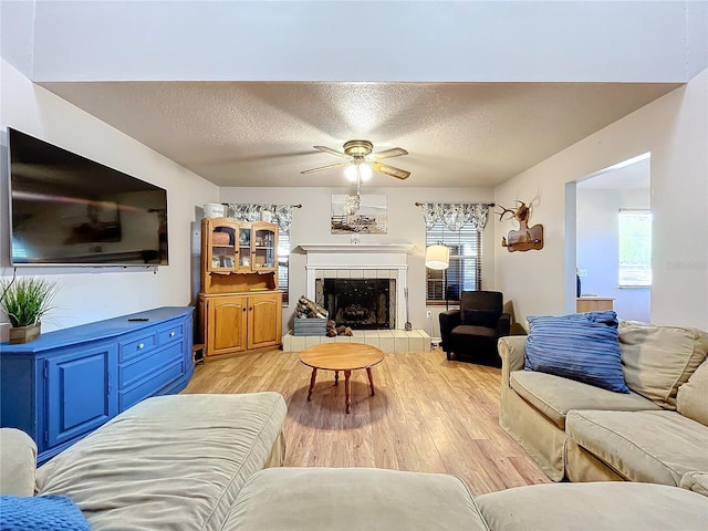 living room featuring a fireplace, light hardwood / wood-style floors, a textured ceiling, and plenty of natural light