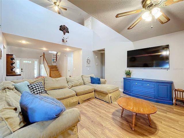 living room featuring ceiling fan, high vaulted ceiling, a textured ceiling, and light hardwood / wood-style flooring