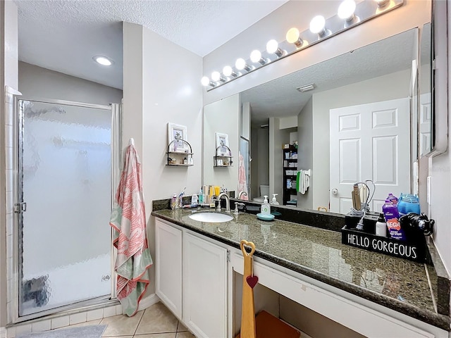 bathroom with vanity, a shower with shower door, tile patterned flooring, and a textured ceiling