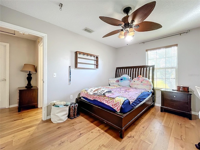 bedroom featuring ceiling fan, a textured ceiling, and light wood-type flooring