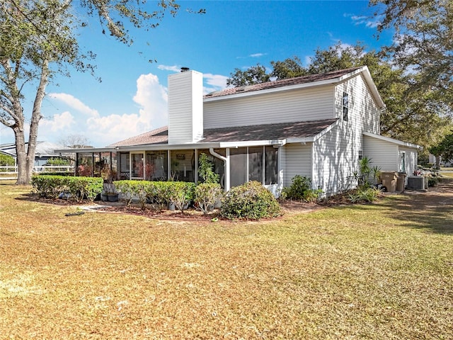 back of property with cooling unit, a yard, and a sunroom