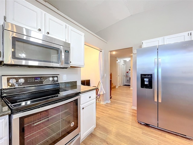 kitchen featuring white cabinetry, stainless steel appliances, vaulted ceiling, and light wood-type flooring