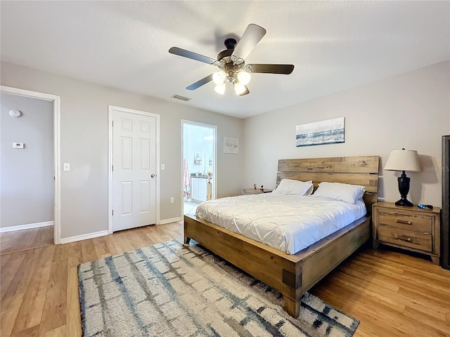 bedroom with light wood-type flooring, ceiling fan, and ensuite bathroom