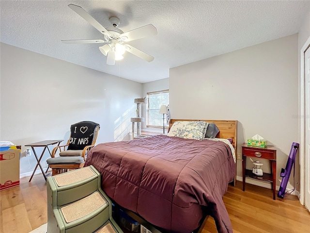 bedroom featuring ceiling fan, light hardwood / wood-style floors, and a textured ceiling