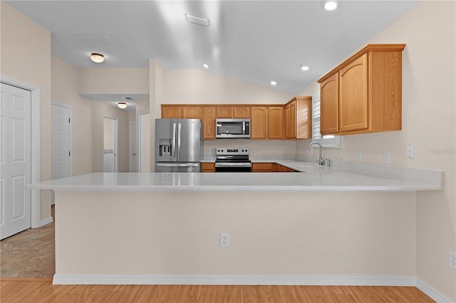 kitchen featuring stainless steel appliances, kitchen peninsula, sink, and light hardwood / wood-style flooring